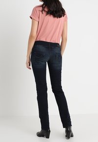 Mörka denimjeans med en figurnära design, med bakfickor och en mjuk textur. Kombinerat med en rosa t-shirt med rund halsringning.