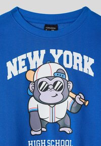 Felpa blu in cotone con una grafica di una scimmia in uniforme da baseball, testo centrato che dice "NEW YORK" e un'accenno di mazza.