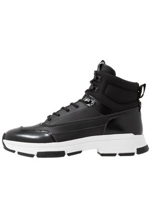 Czarny wysokiej klasy sneaker z białą masywną podeszwą, wyściełanym kołnierzem wokół kostki, sznurowaniem z przodu i logo Calvin Klein na podeszwie.