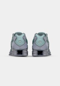 Zapatillas que presentan una combinación de colores gris y verde azulado, materiales de malla y sintéticos, forma redondeada y un sistema de amortiguación visible.