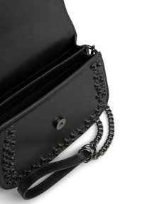 Zwarte leren handtas met een kettinghengsel, glanzende hardware en decoratieve studs aan de voorkant. Het interieur heeft meerdere compartimenten.