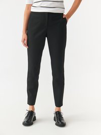 Black tapered pants with a smooth texture, featuring side pockets. Paired with black lace-up shoes and a white striped top.