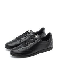 Sneakers din piele neagră au vârful rotunjit, șireturi plate și ochiuri argintii. Designul include cusături subtile și o talpă texturată.