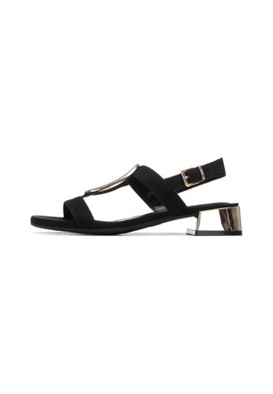 Sandalia de ante negro con diseño plano, con un acento metálico y correa ajustable en el tobillo. Tacón bajo y brillante en bloque que aporta estabilidad.