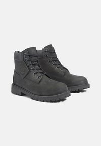 Botas de senderismo de cuero negro con puntera reforzada, lazos metálicos para los cordones y una suela de goma texturizada. Presentan un detalle de logo en relieve en el lateral.