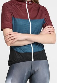 Lyhythihainen pyöräilypaita, jossa on maroon yläosa, sininen keskiosa ja musta alaosa. Paidassa on etuvetoketju, teksturoitu kangas ja sporttinen muotoilu.