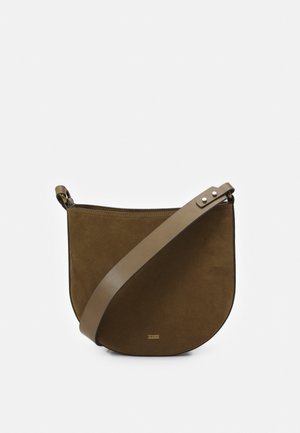 Brązowa zamszowa torebka w kształcie półksiężyca z szerokim skórzanym paskiem na ramię i małym złotym logo marki z przodu na białym tle.