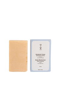 Barra di pulizia solida rettangolare beige accanto a un imballaggio blu e bianco etichettato "Pulizia Solida Idratante per il Corpo" con miele e burro di karité, fatto in Italia.