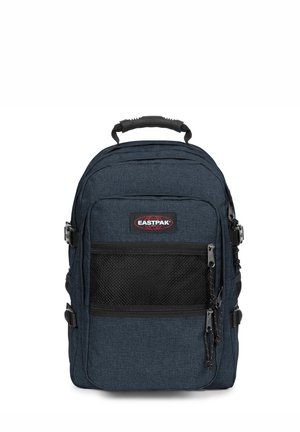 Mochila de tela azul oscuro con un bolsillo frontal de malla, correas acolchadas, asa superior y cierres de cremallera. Presenta una etiqueta de marca en la parte frontal.