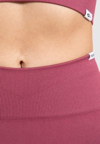Ribbelstof met rek in een diepe rozenkleur vormt een naadloze crop top en een hoge tailleband, met kleine merketiketten.
