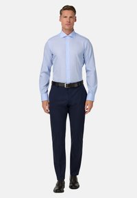 Jasnoniebieska koszula z kołnierzykiem o spiczastym kształcie, długimi rękawami i zapięciem na guziki, w zestawie z granatowymi spodniami i czarnymi butami.