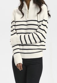 Suéter de punto blanco con rayas horizontales negras, cuello con media cremallera, puños y dobladillo acanalados, que presenta un tejido texturizado.