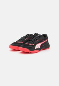 Zapatos deportivos negros con una parte superior de tela texturizada, acentos en rosa y una suela roja. Presenta un diseño de cordones y un logotipo de marca prominente.