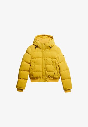 Giacca a vento gialla con design cropped, cappuccio e due tasche frontali. Presenta chiusure a scatto e polsini a costine per calore e vestibilità.