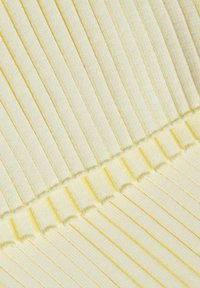 Gros plan sur un tissu tricoté côtelé jaune pâle avec des rayures verticales et un détail de couture horizontale au centre.