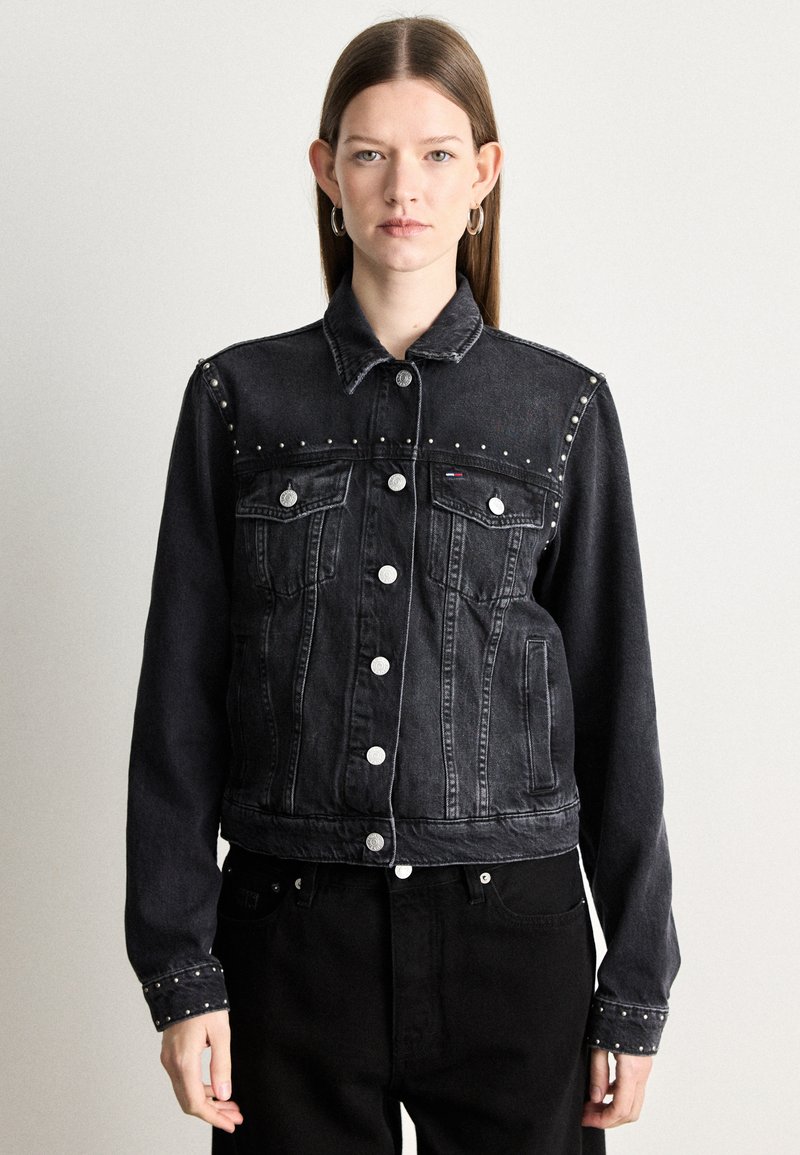 Mustat farkku takki, jossa on hopeiset niitit hartioilla, nappikiinnitys ja kaksi rintataskua. Ominaisuuksiin kuuluu klassinen kaulus ja lyhyt leikkaus.