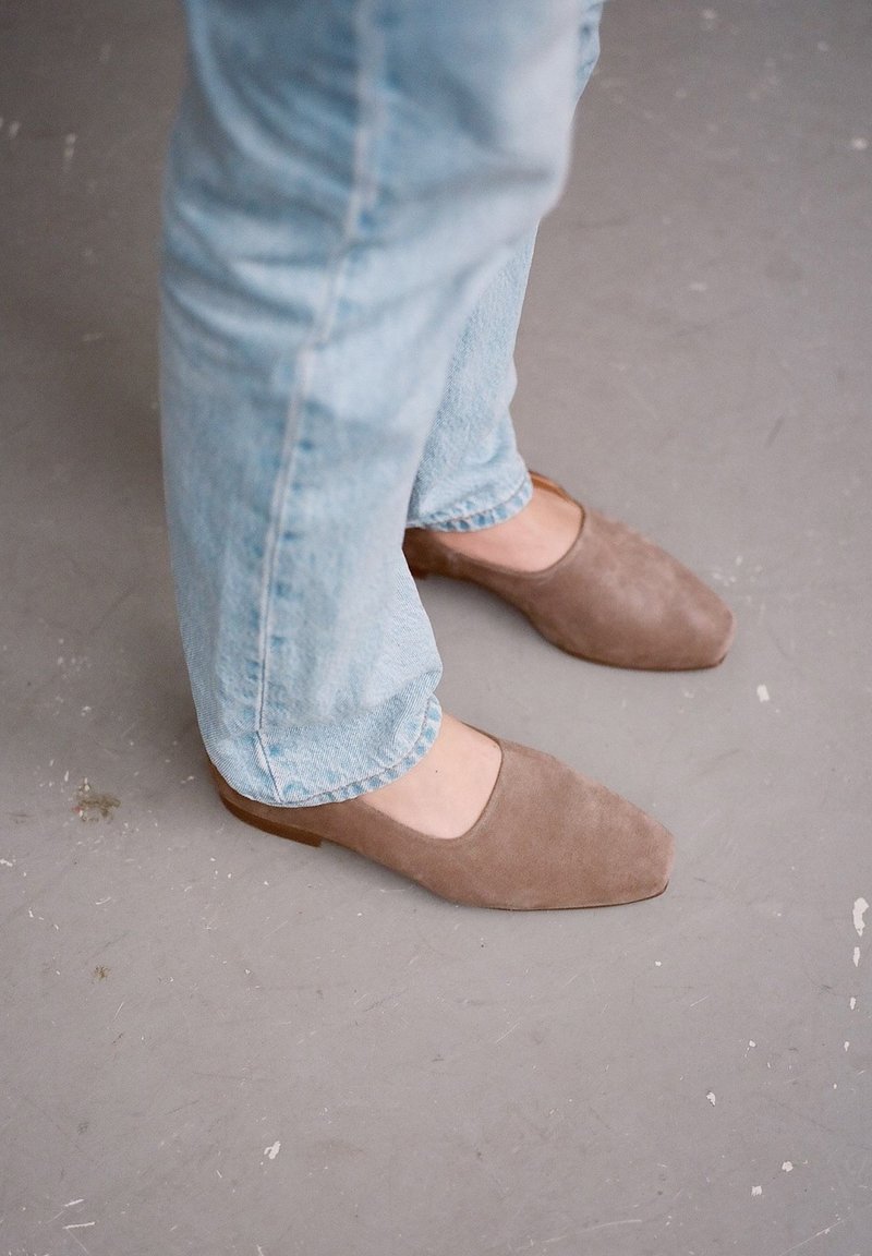 Suedesandaler i taupe-färg med kvadratisk tådesign och låg klack, tillsammans med ljusblå, något uppvikta jeans.