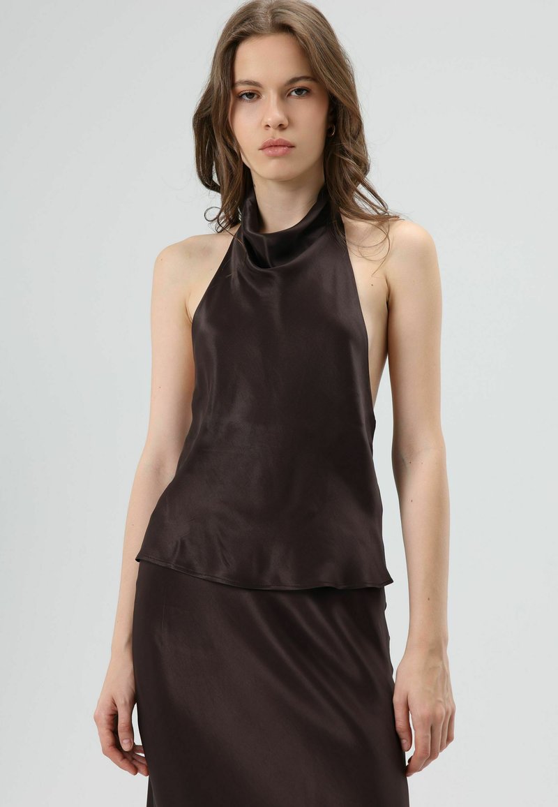 Mouwloze bruine satijnen haltertop met een gedrapeerde halslijn, gladde textuur en een losse pasvorm tot aan de taille, gecombineerd met een bijpassende rok.
