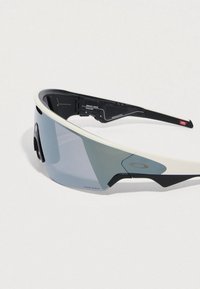 Sportsolbriller med en let hvid ramme, gråtonede linser og sorte detaljer. Har justerbare stænger for komfort.