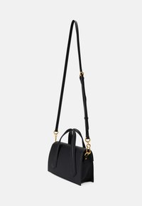 Sac à main en cuir noir avec une forme structurée, deux poignées supérieures et une bandoulière amovible. Des accents en matériel doré agrémentent le design.
