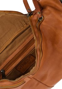 Tan leather handbag interior with a zipper compartment and a fabric lining. Features a label embossed with "VENEZIA Genuine Leather."