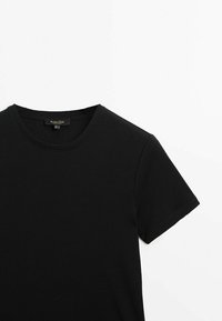 T-shirt nera a coste con scollo rotondo e maniche corte. Il tessuto sembra morbido con una fine texture. Etichetta visibile sul collo.