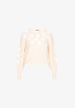 Pull en tricot couleur crème avec des appliqués floraux, des manches ballons et un motif texturé sur les côtés. Design à longueur cropped.