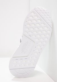 Vit idrottssko med hexagonmönstrad sula, texturerat mönster och varumärkesdetalj. Lättviktig design som passar för olika ytor.