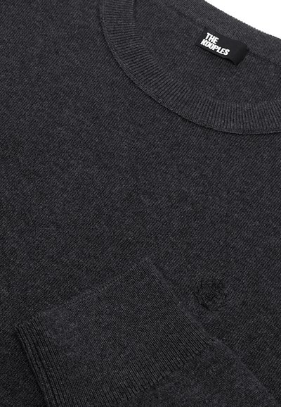 Maglione a maglia grigio scuro con scollatura rotonda, polsini a coste e un piccolo logo sul petto. Texture liscia e design classico.