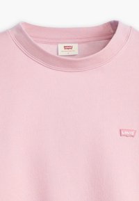 Sweatshirt rose à col rond en coton doux, avec un petit logo brodé Levi's sur la poitrine gauche. Texture lisse avec un col ribb. 