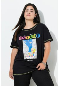 Camiseta negra de gran tamaño con acentos en neón, que presenta un gráfico de zapatillas coloridas, jeans desgastados y un texto que dice "TODO LO QUE NECESITAS ES ÚNICO."