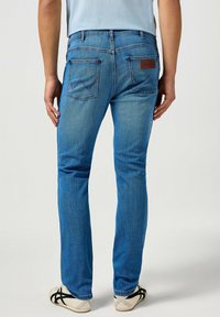 Vaqueros de mezclilla azul con un diseño de pierna recta, que cuentan con dos bolsillos traseros, detalles de costura y una etiqueta de cuero en la cintura.
