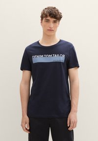 Navy blå bomullst-skjorte med rund hals og korte ermer, med hvit tekst "DENIM TOM TAILOR" og en horisontal blå aksent.