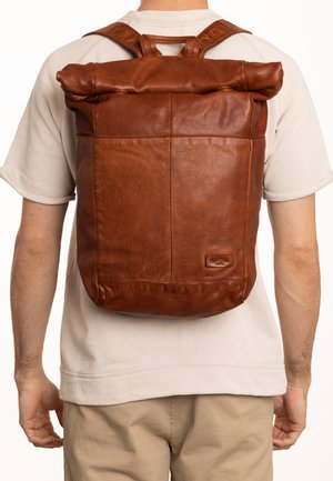 Brown leather roll-top backpack with a textured finish, adjustable straps, and a side pocket. Features a compact, rectangular shape.