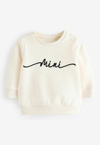 Kremowa bluza wykonana z miękkiego materiału, z długimi rękawami, ściągaczami przy mankietach oraz czarnym haftem "Mini" z przodu.