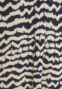 Tessuto di cotone con un motivo astratto ondulato in blu navy e bianco sporco, che mostra una superficie testurizzata con linee e curve audaci.