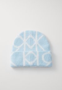 Blå strikket lue med et hvitt geometrisk mønster. Myk tekstur, avrundet topp og oppbrettet design.