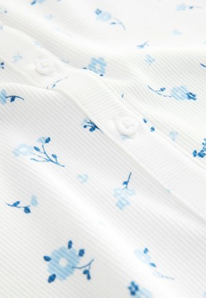 Hvid rippet stof med små lyse og mørkeblå blomsterprint og hvide knapper langs en søm.