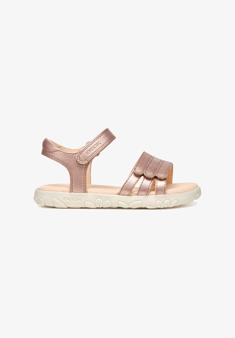 Sandalias sintéticas de color oro rosa con hebillas de Velcro, con la parte trasera abierta y suela de goma blanca con acentos florales. Textura suave, diseño casual.