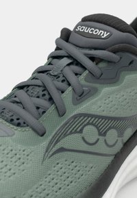 Saucony løbesko med en tekstureret grøn overdel, grå snørebånd og et sort logo på den polstrede tunge, der har en hvid sål.