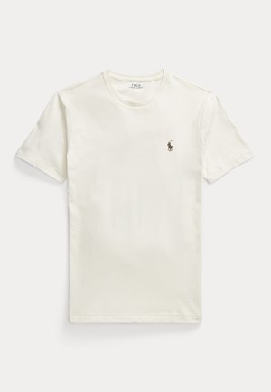 T-shirt blanc uni à manches courtes avec un petit logo de joueur de polo brodé sur la poitrine gauche, posé à plat sur un fond clair.