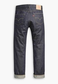 Jeans de denim azul oscuro con dobladillos enrollados, que presentan dos bolsillos traseros con costuras curvas y una etiqueta de cuero en la cintura.