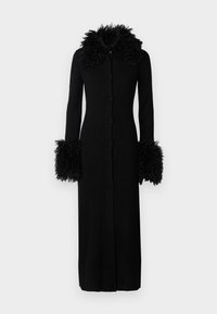 Zwarte ribbeljurk met lange mouwen, voorzien van een donzige afwerking bij de kraag en manchetten. Het ontwerp heeft een sluiting met knopen aan de voorkant en een jurk tot op de vloer.