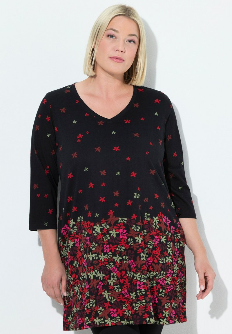 Zwarte tuniek met een V-hals en driekwartmouwen, met een bloemenpatroon in rood, roze en groen over de stof.