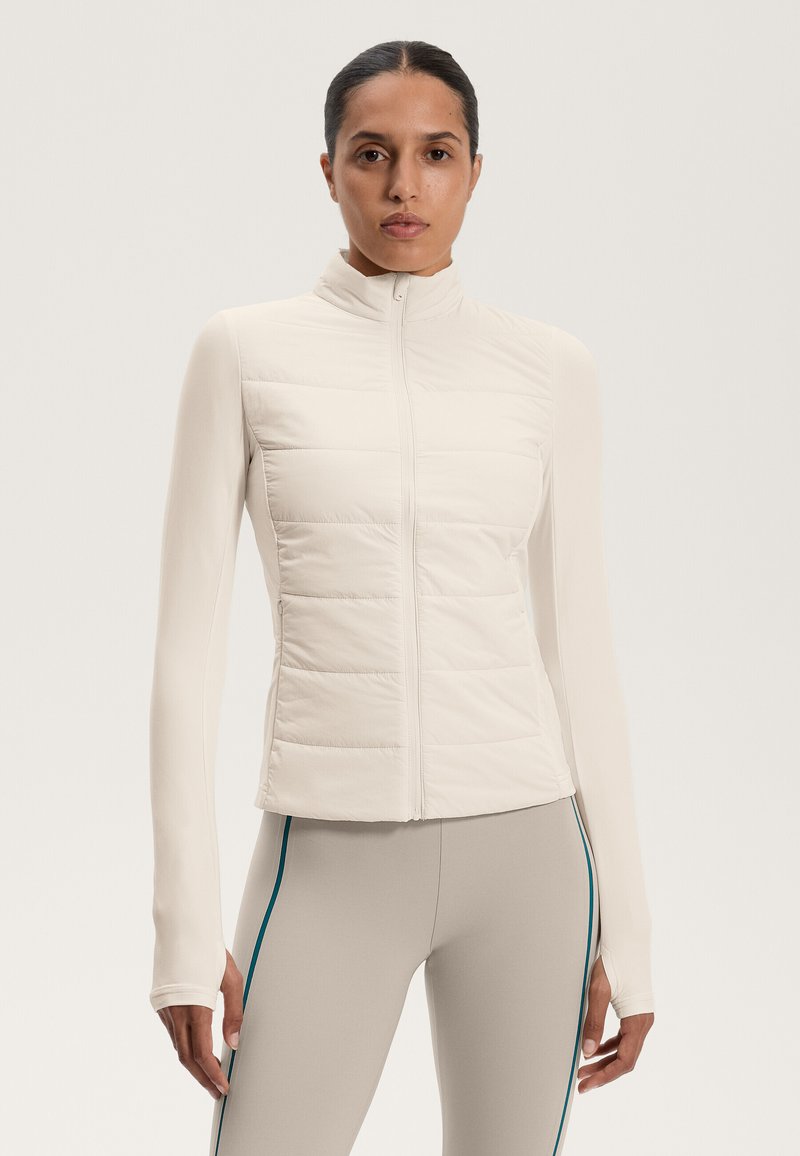 Lightweight, cream-colored puffer jacket with a zip closure and panel detailing, featuring long, fitted sleeves and smooth fabric texture.