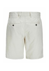 Pantalones cortos de color beige claro hechos de una tela texturizada. Presentan una cinturilla con pasadores para cinturón, dos bolsillos traseros con botones negros y piernas rectas.