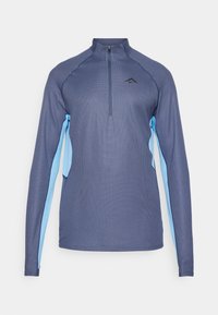 Chemise de sport à manches longues en bleu foncé avec des panneaux latéraux bleu clair, fermeture éclair quart de zip et tissu texturé. Présente un logo sur la poitrine.