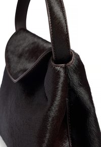 Svart pälsväska med en slät textur, med en strukturerad form, rundad klaff och mörka läderdetaljer på handtaget och kanterna.