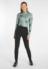 Długi rękaw rowerowy w miętowym kolorze z czarnym wzorem w gwiazdy, połączony z czarnymi dopasowanymi dresami z bocznymi zamkami i elastycznym pasem.