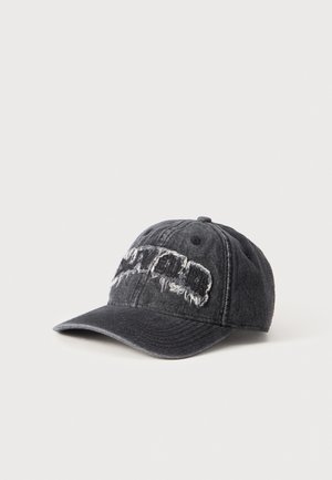 Casquette de baseball en denim gris foncé, avec une visière incurvée et une inscription blanche à l’aspect usé sur le devant, sur un fond uni.